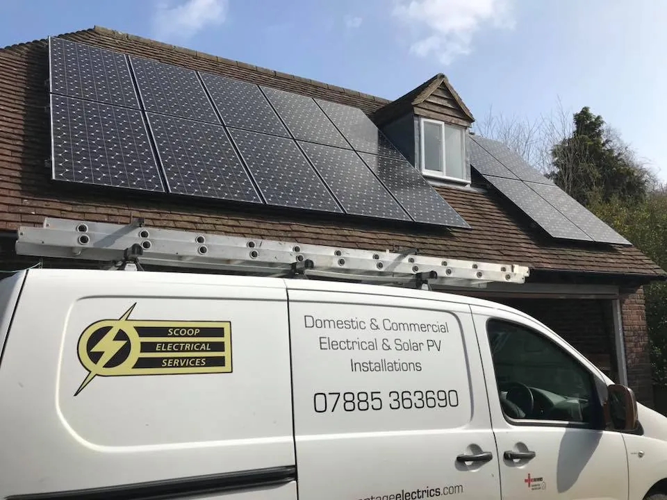 The Scoop Electrical Services van parked below a house roof fitted with solar panels